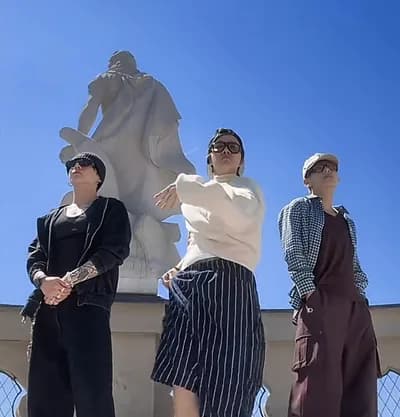 Three people dancing outside under a blue sky