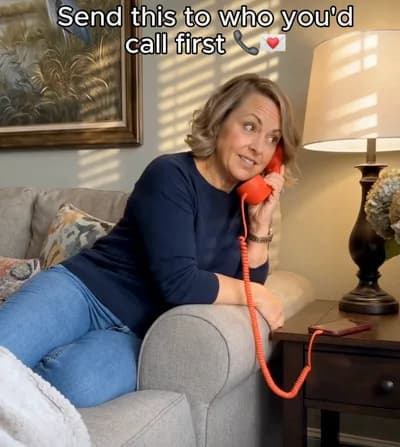 A woman sitting on a sofa with a red telephone