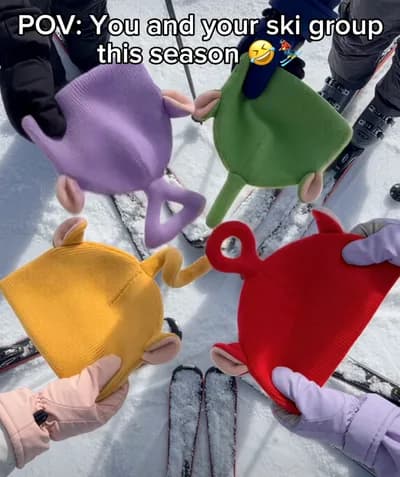Four colorful character hats held together on a ski slope